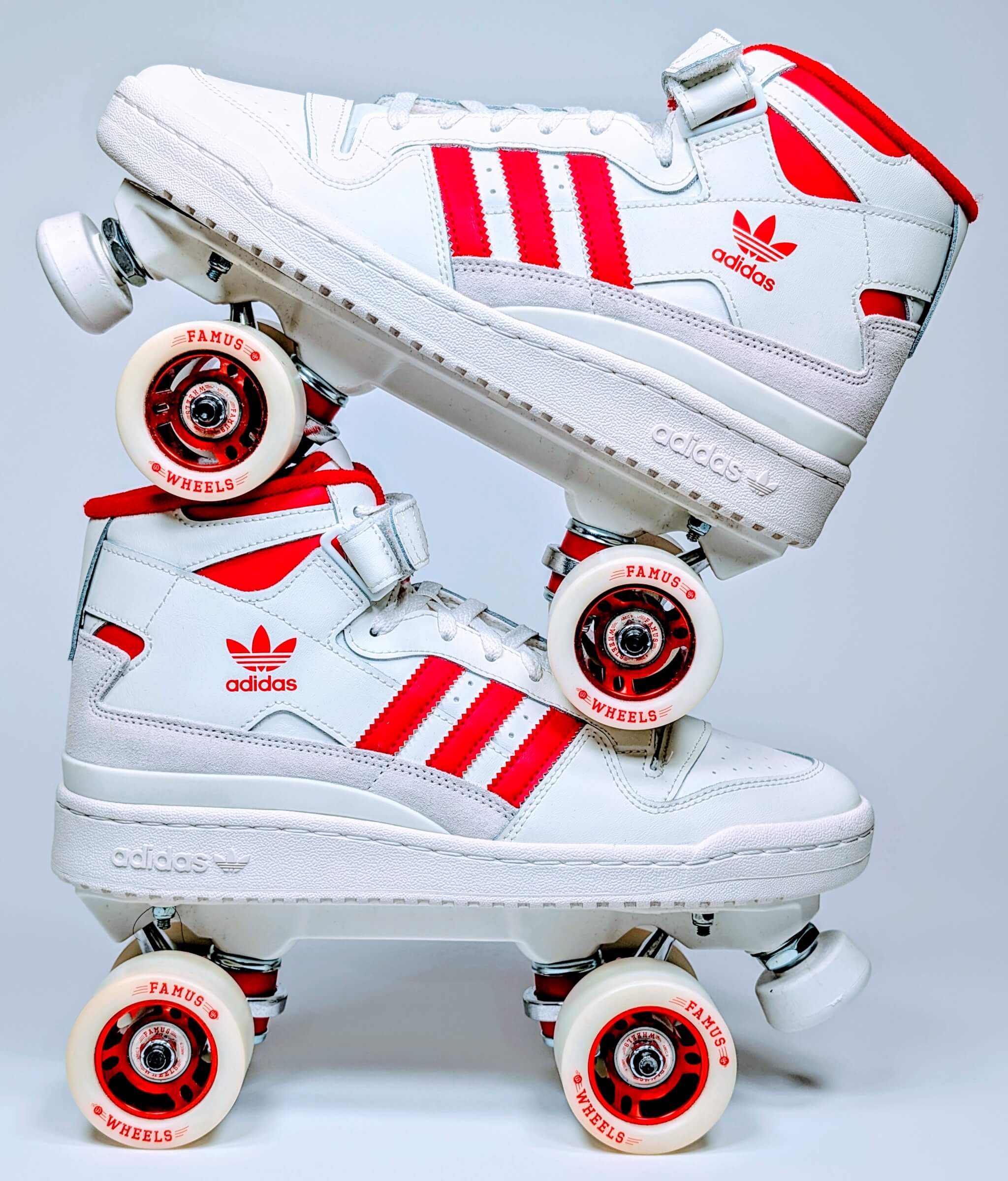 Side view of Loumy's Adidas Forum Redline roller sneakers stacked one over the other, red and white with metallic rims