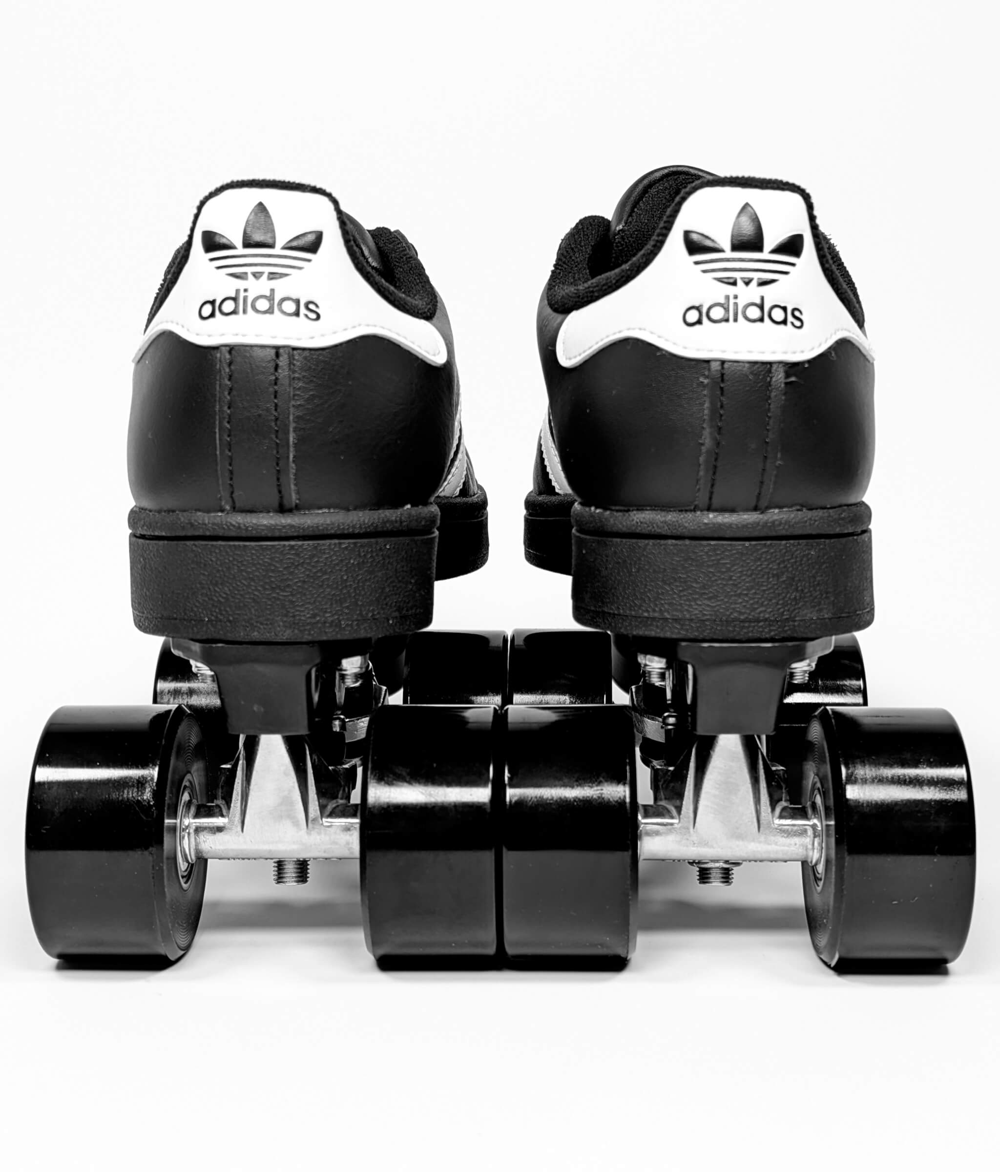 Back view of Loumy’s Adidas Superstar roller sneakers in black with white stripes and heel Adidas logo