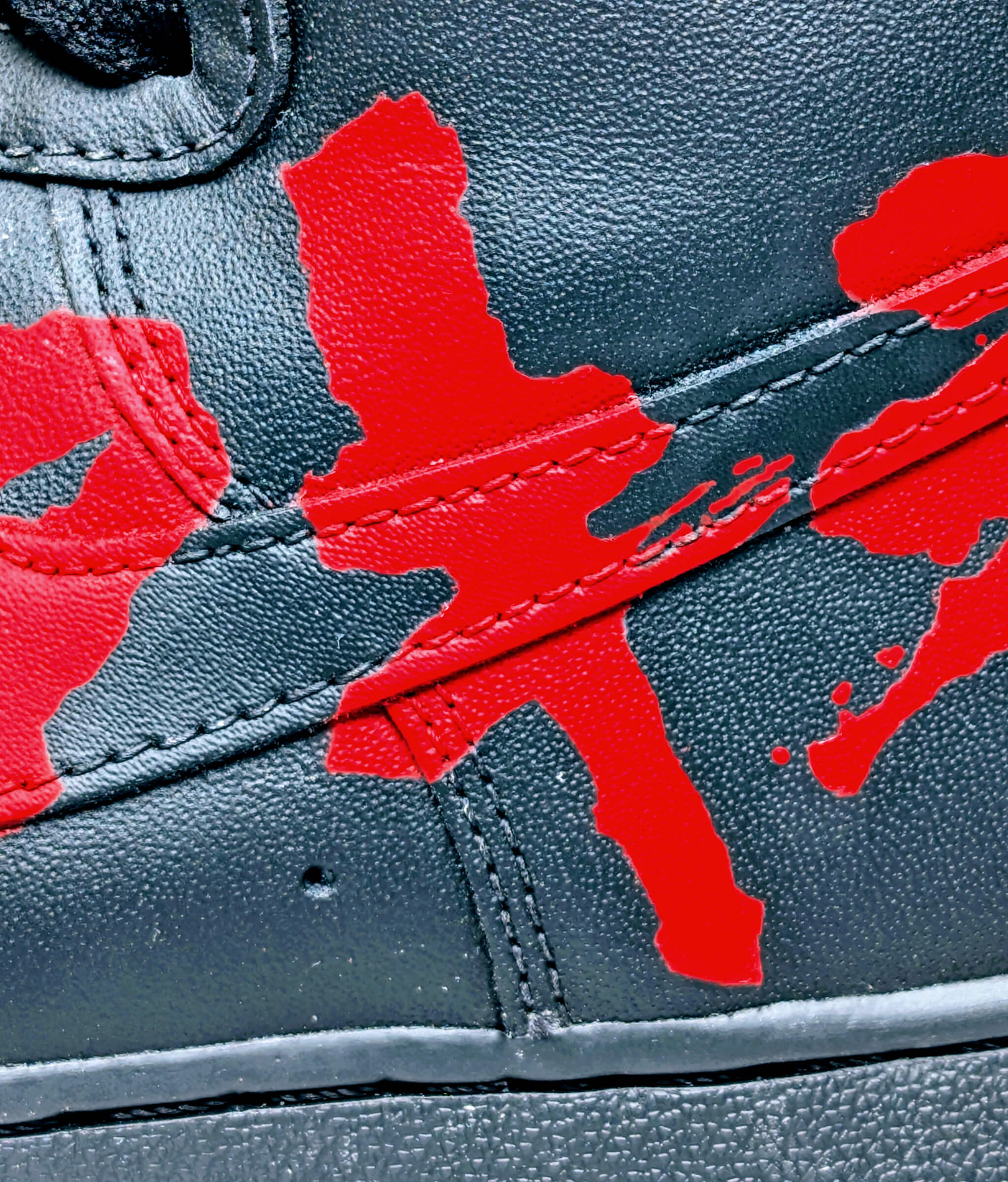 Close-up of custom red Akira lettering painted over the swoosh of Loumy x Kazy’s black Nike Air Force 1 High