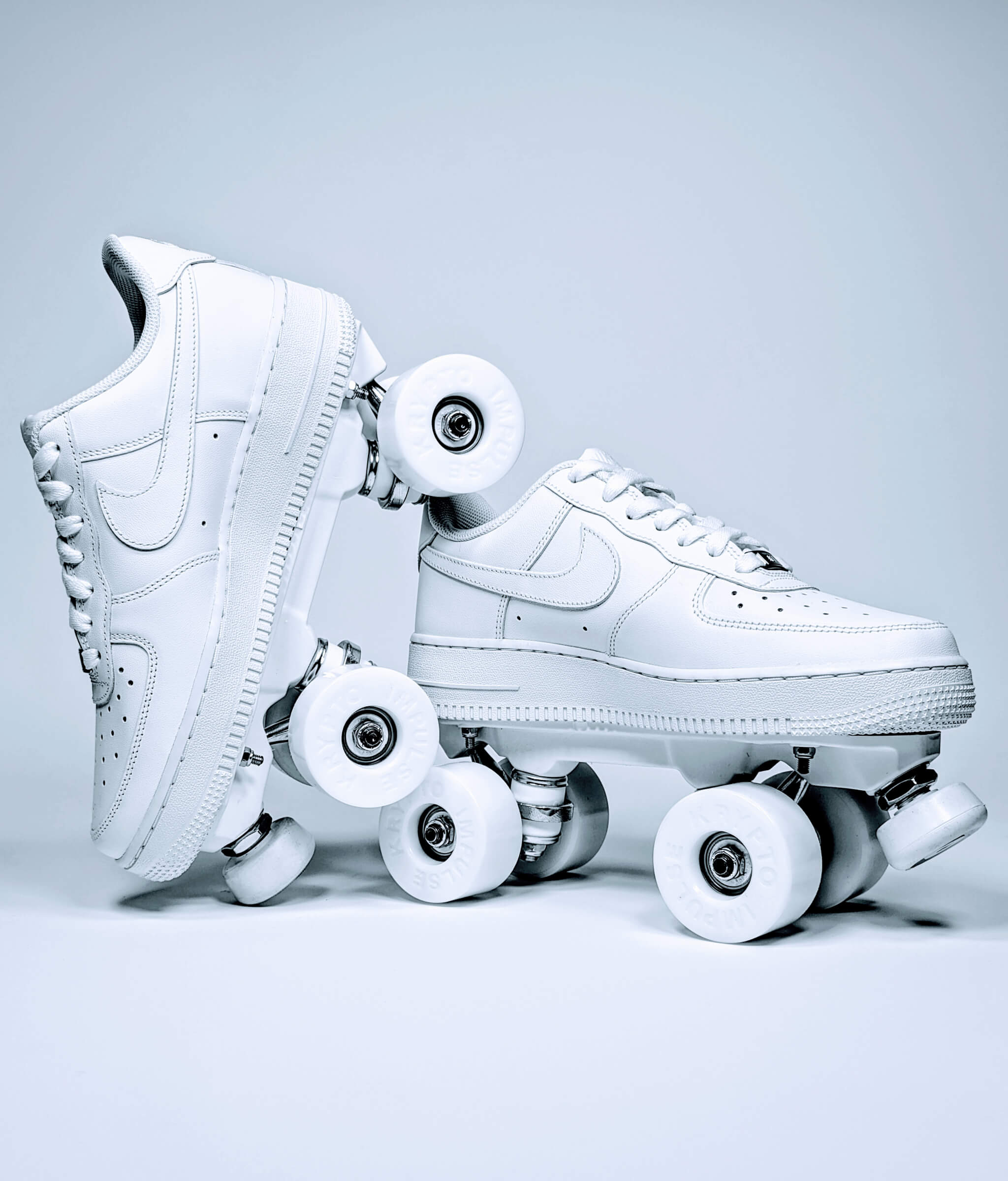 Loumy roller sneakers made from all white Nike Air Force 1 Low, with one tilted and balanced on the other