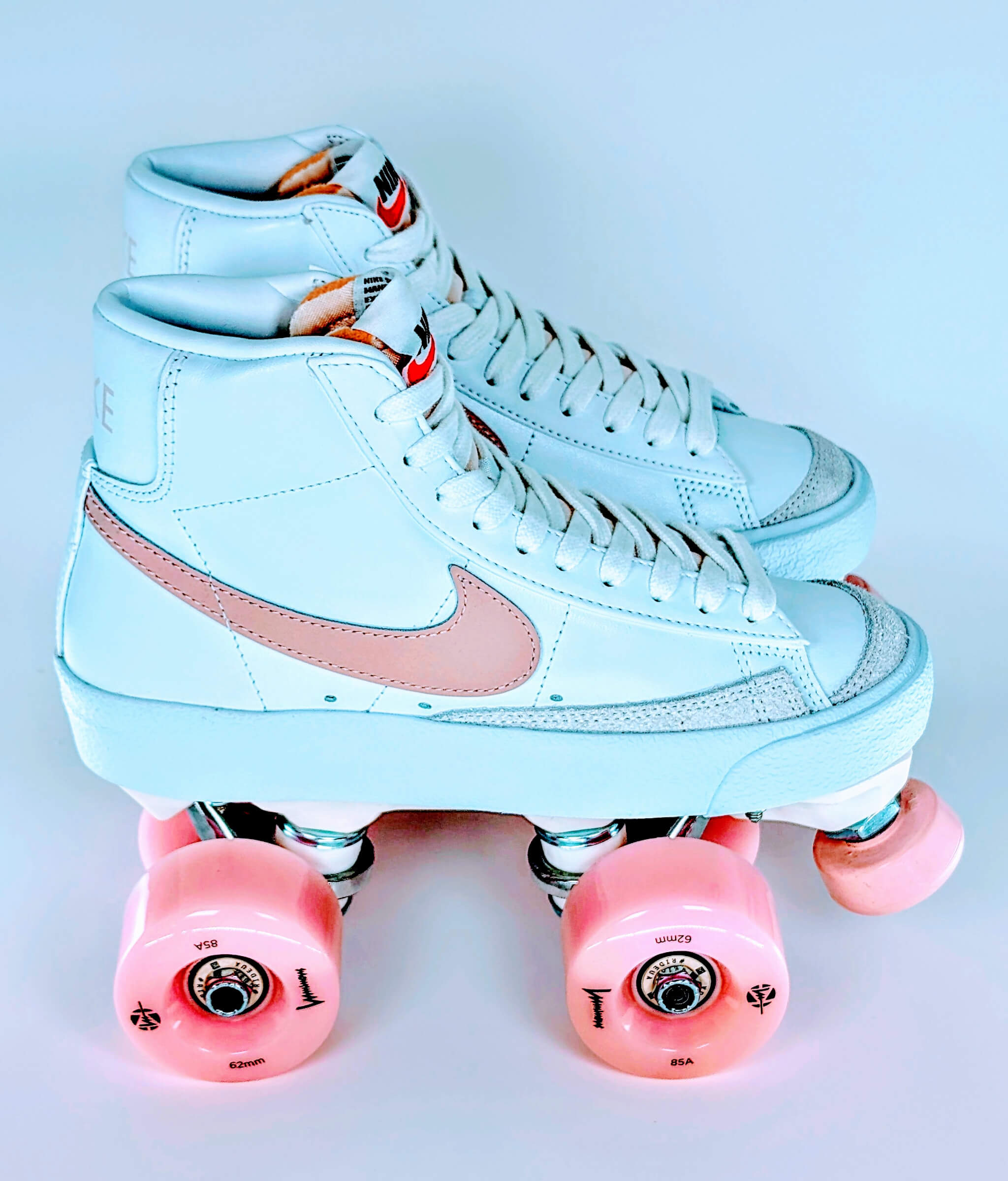 Loumy's Loumynous Blazer roller sneakers made from white Nike Blazer Mid ’77 with pink swoosh and glowing pink LED wheels, shown side by side in profile view