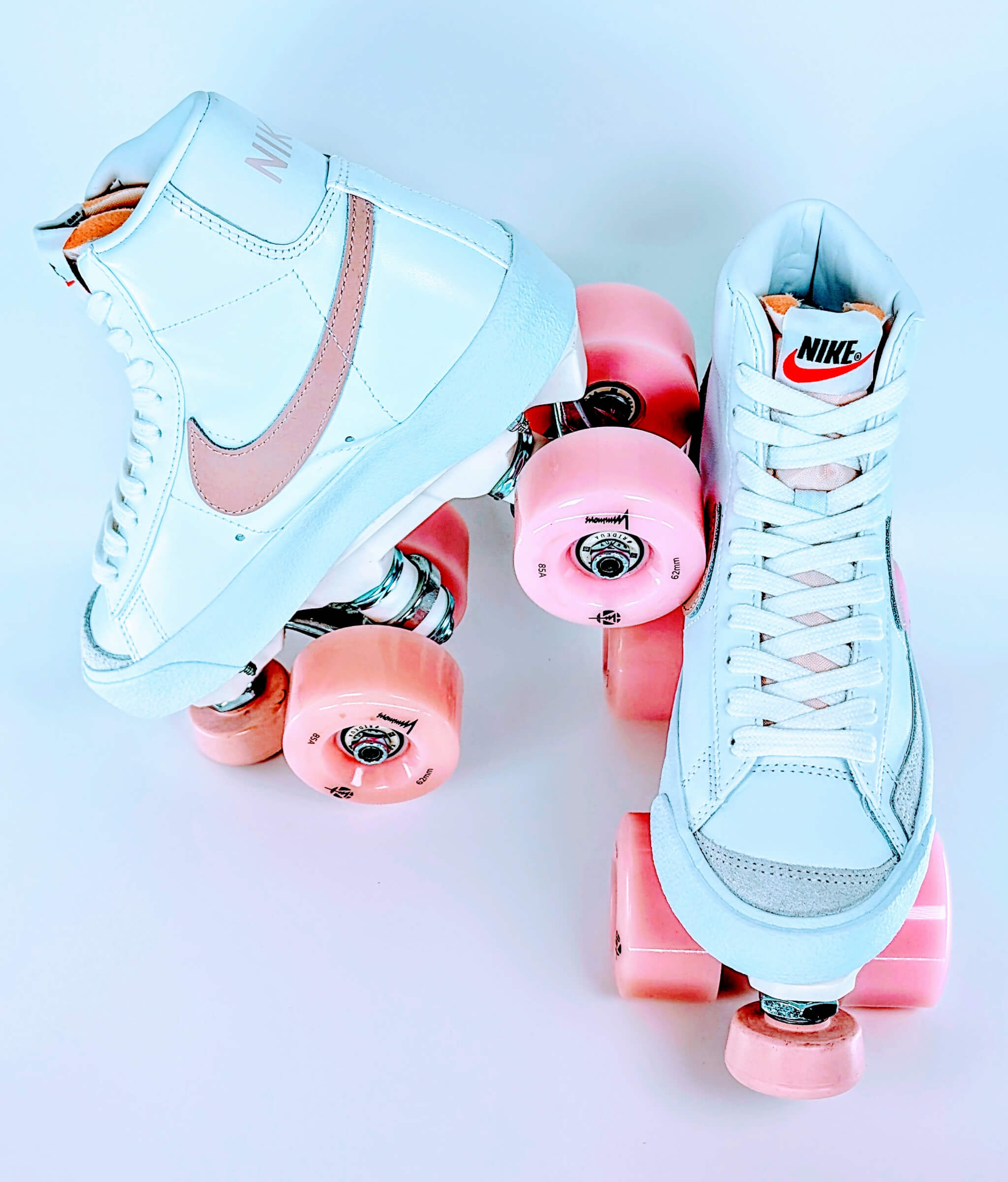 Loumy's Loumynous Blazer roller sneakers made from white Nike Blazer Mid ’77 with one tilted sneaker balanced on the other, featuring pink LED wheels