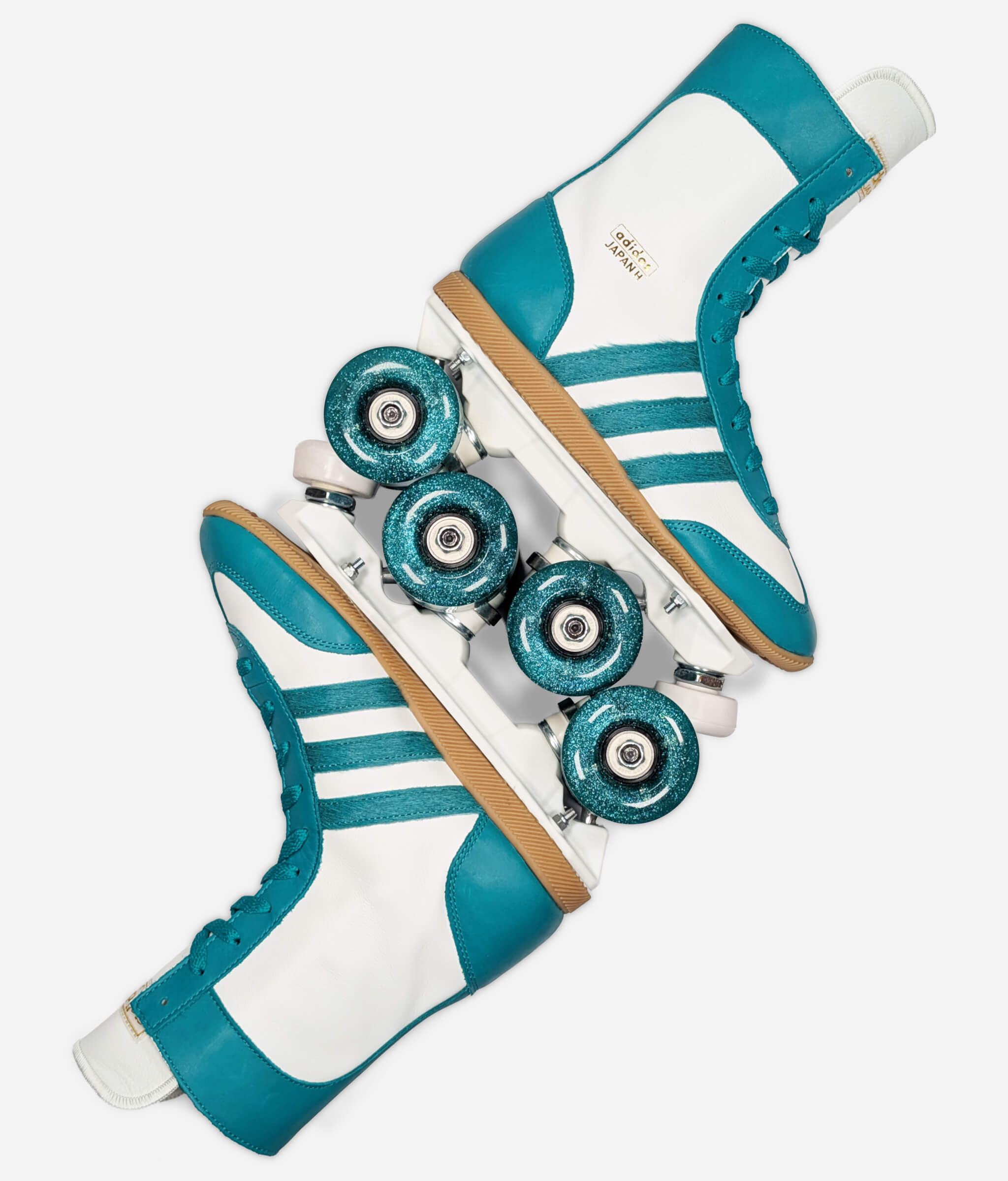 Adidas Japan H Teal roller skate sneakers by Loumy’s World layed with interlocked wheels, and white and teal leather