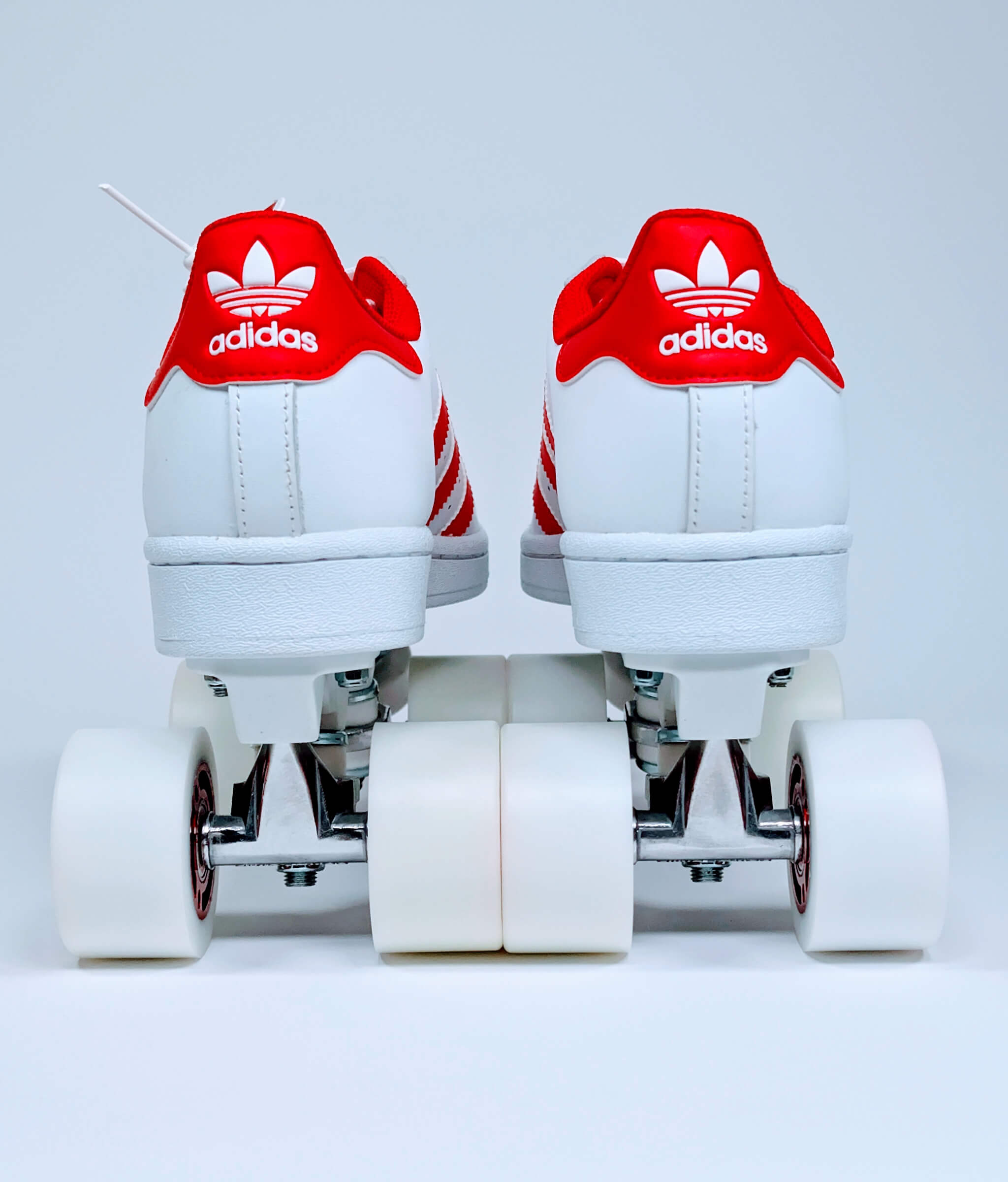 Back view of Loumy’s Adidas Superstar roller sneakers in white with red stripes and heel Adidas logo