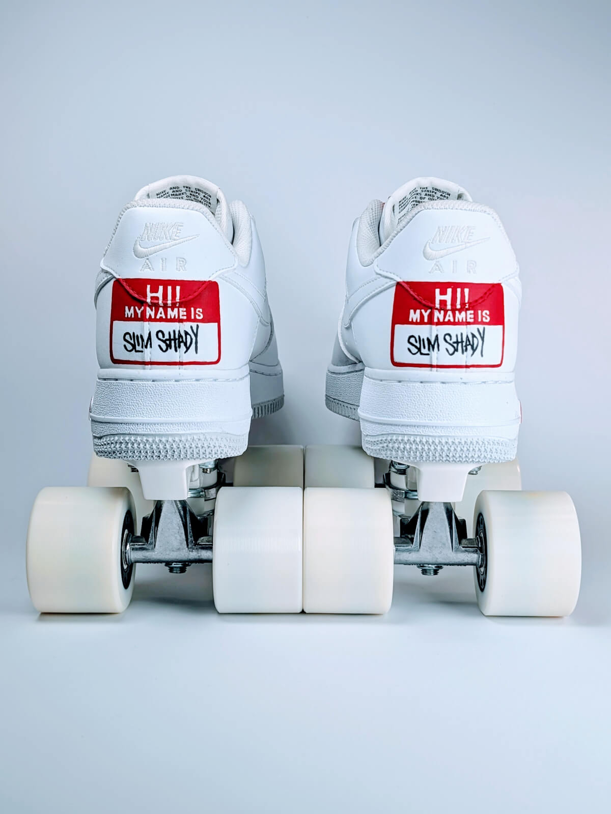 Rear view of white Nike Air Force 1 Low roller skate sneakers by Loumy’s World with “Hi! My name is Slim Shady” on the heels