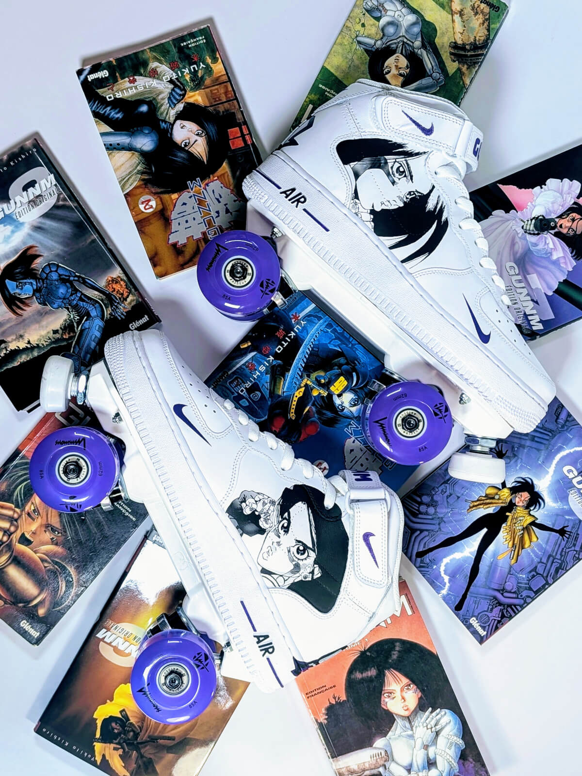 Overhead view of white Nike Air Force 1 Mid roller skate sneakers by Loumy’s World arranged on Gunnm manga volumes, with purple wheels and Gally portraits hand-painted by Kazy