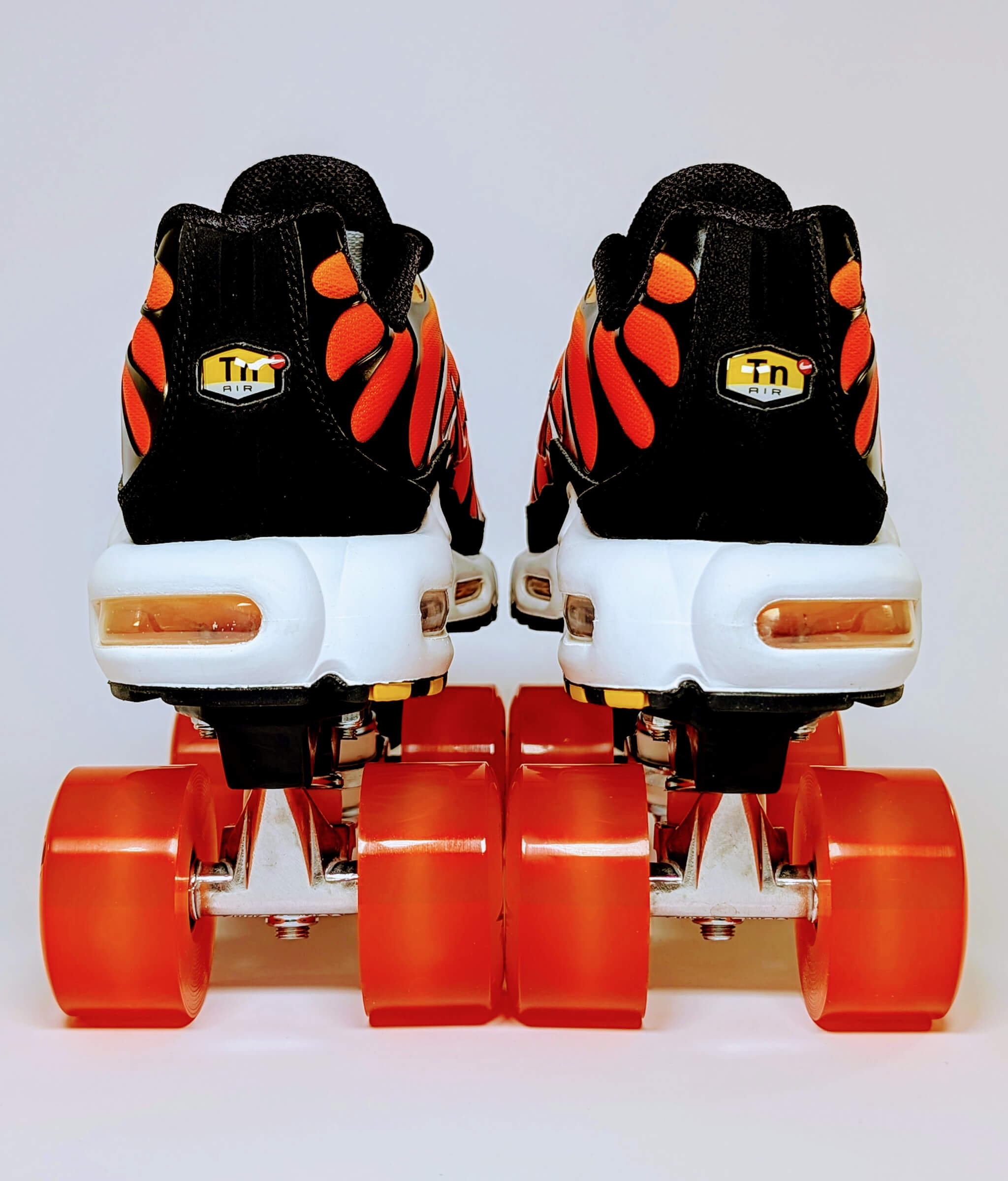 Back view of Nike Air Max Plus roller sneakers by Loumy in yellow and orange with glowing orange LED wheels and visible air cushioning