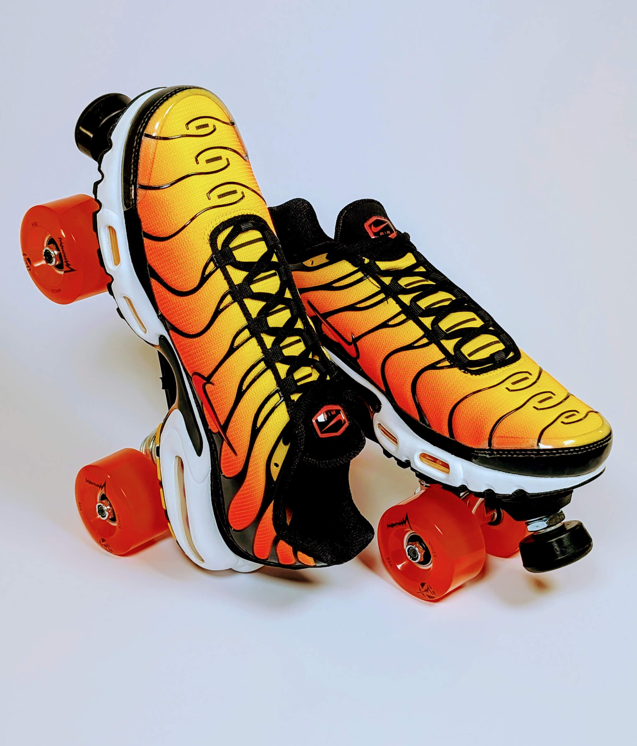 Loumy Air Max Fire roller sneakers made from Nike Air Max Plus in yellow and orange, one flat and one standing on the heel in side-by-side view, with orange LED wheels