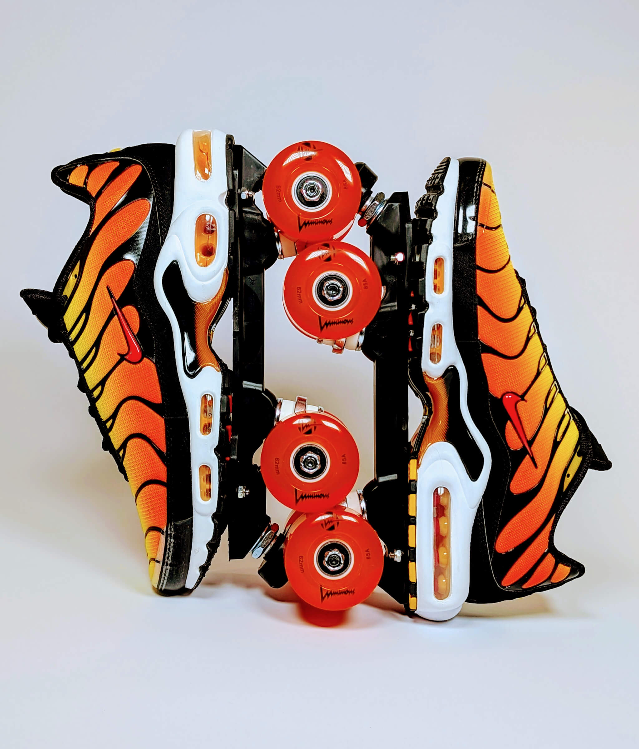 Loumy's Air Max Fire roller sneakers made from yellow and orange Nike Air Max Plus, displayed vertically with interlocked wheels and glowing orange LED lights