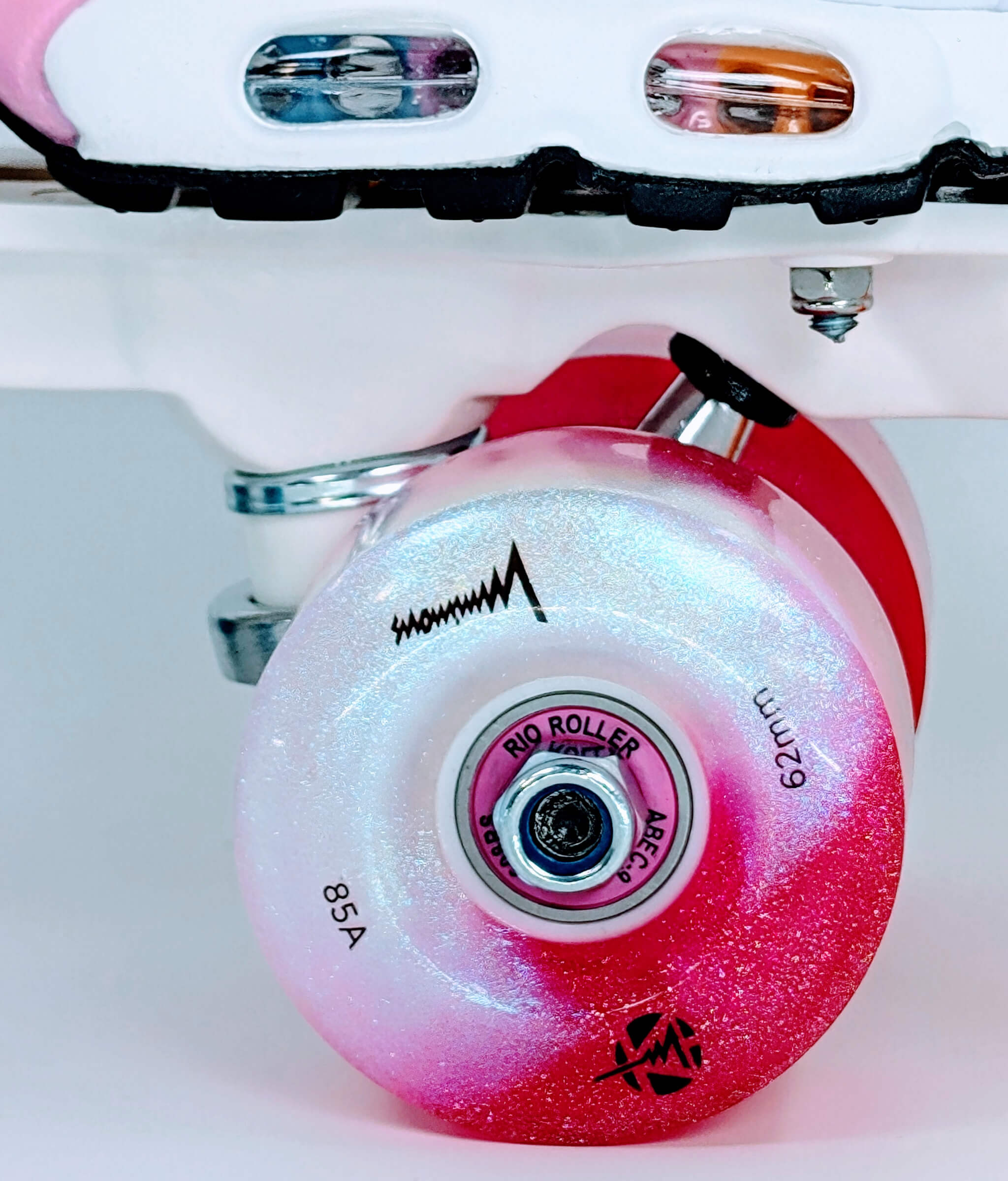 Close-up of glowing front wheel on Loumy's Air Max Plus Summer Gradient roller sneakers, with pink and white LED lights and pink bearing visible