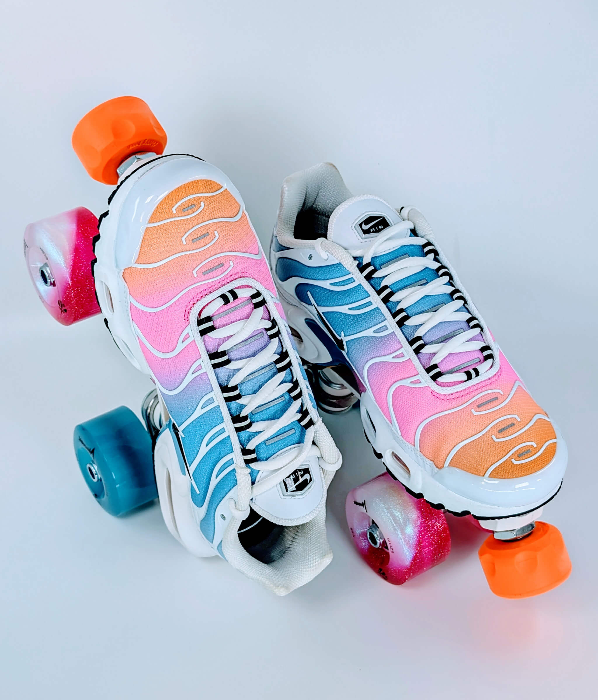 Loumy's Air Max Plus Summer Gradient roller sneakers, with one flat and the other standing on its heel, showing glowing pink and blue wheels