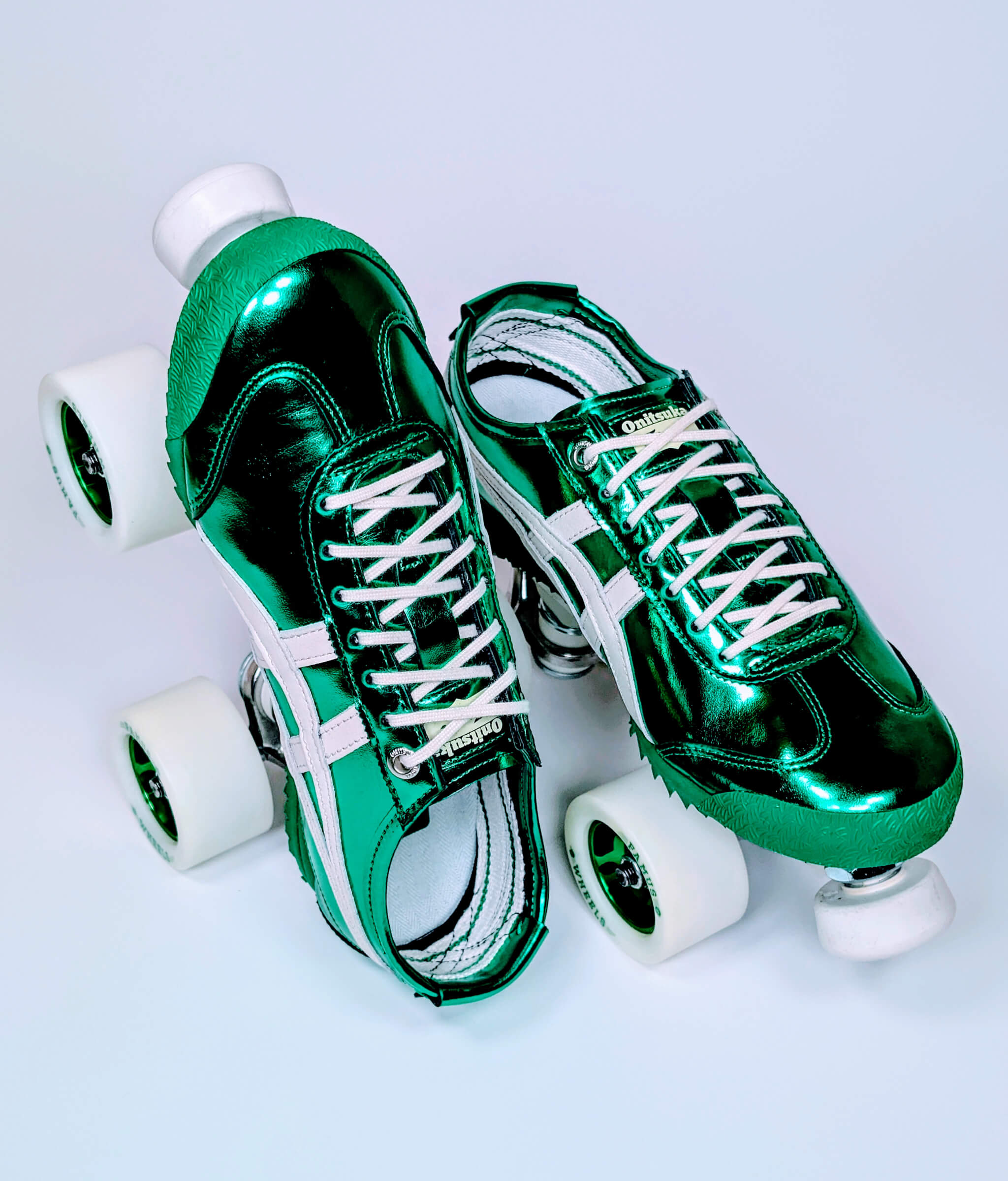 Loumy's Onitsuka Mexico Metallic Series roller sneakers in metallic green, with one flat and the other standing on its heel, featuring green metallic rims