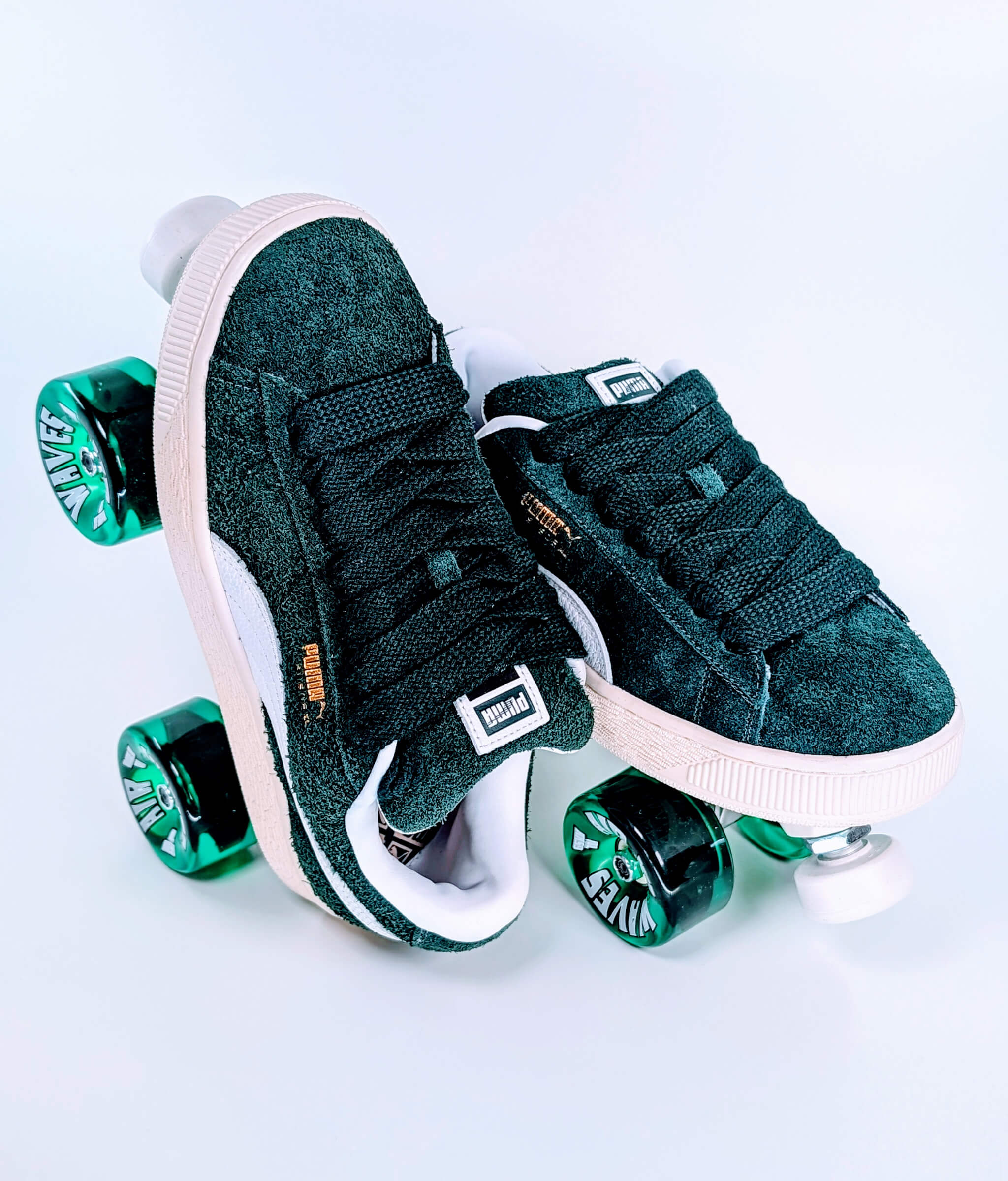 Loumy's Puma XL Hairy Suede roller sneakers in dark green, with one flat and the other standing on its heel, featuring translucent green wheels